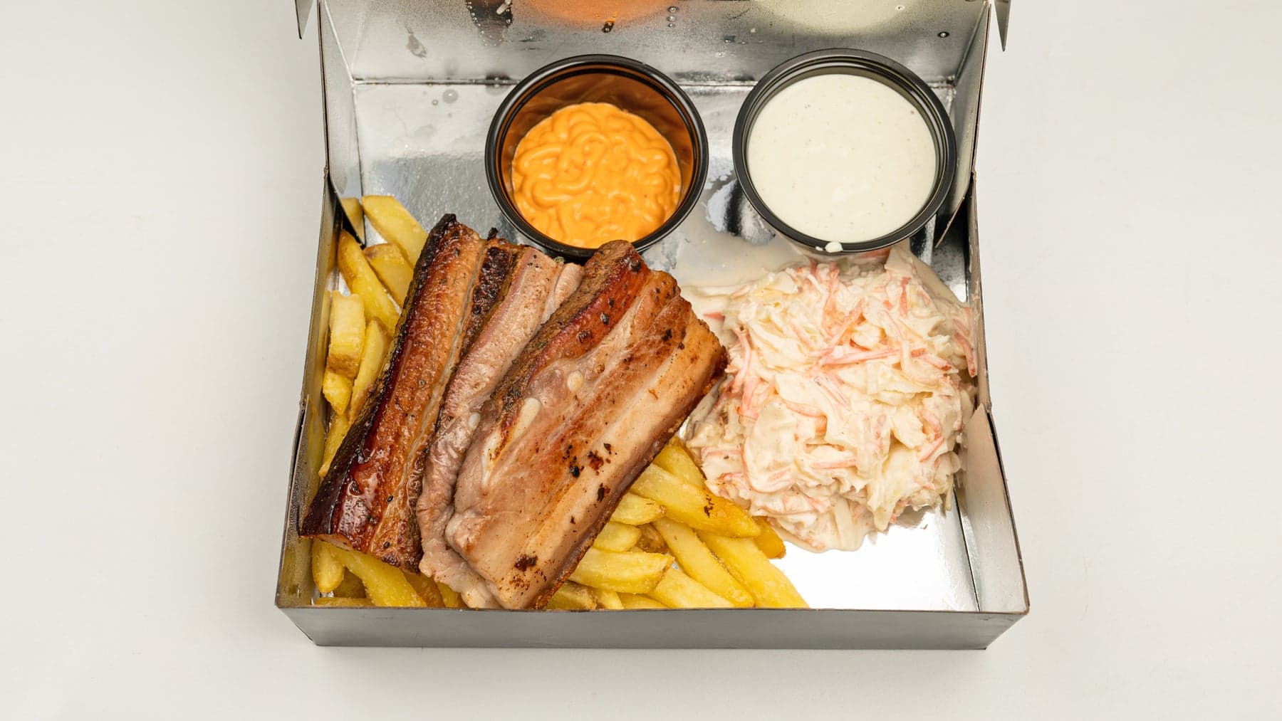 Crispy Pork Belly with crackled skin, boxed up with fries, coleslaw and house sauces